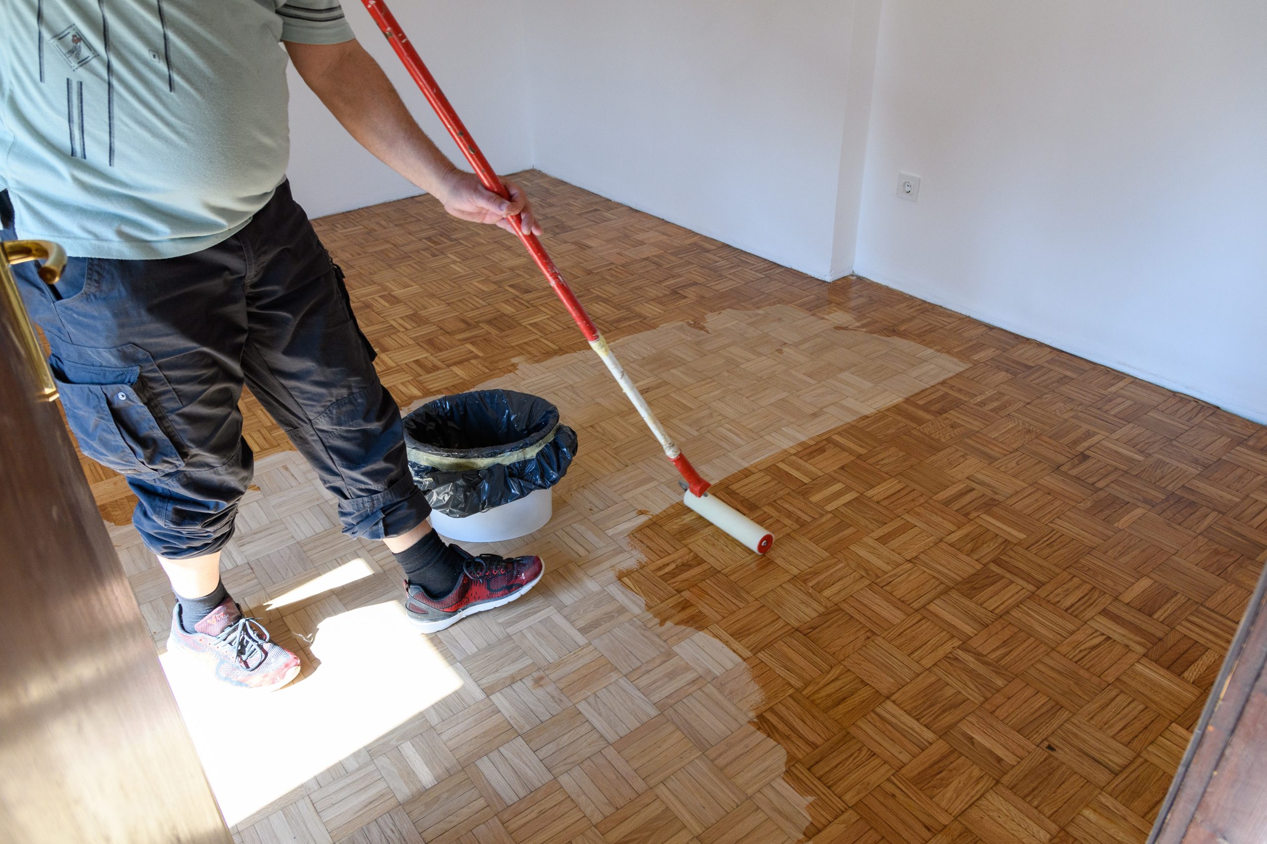 Man applying lacquer finish on hardwood floor