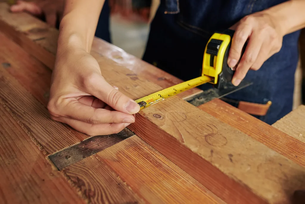Professional installer measuring and cutting hardwood planks with precision.